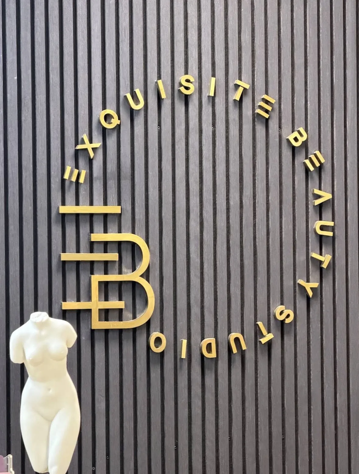 Messing-Monogramm „Exquisite Beauty Studio“ auf der Lamellenwand